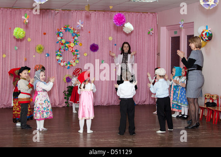 Les enfants avec les enseignants à jouer sur la scène en Fédération de la maternelle. Maison de vacances pour les consacré la journée de la femme, Russie Banque D'Images