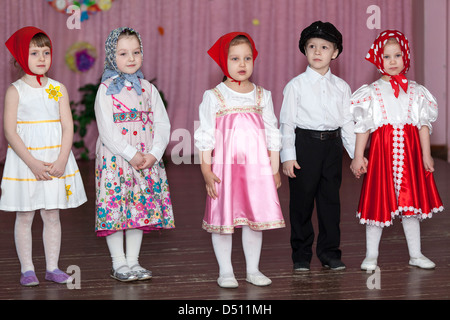 Cute garçons et filles dans les vêtements traditionnels russes dans le jardin d'enfants assis sur les chaises en classe. La Russie Banque D'Images