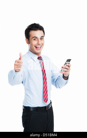 Businessman showing Thumbs up sign tandis que la messagerie texte sur un téléphone mobile Banque D'Images