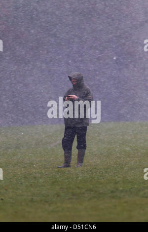 Abington Park Northampton UK. 22 mars 2013. Tôt le matin, la pluie, le grésil et la neige dans la région de Abington Park Northampton UK en tant que propriétaire d'un chien utilise son téléphone portable en attendant son chien. Credit : Keith J Smith/Alamy Live News Banque D'Images