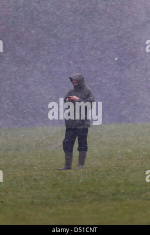 Abington Park Northampton UK. 22 mars 2013. Tôt le matin, la pluie, le grésil et la neige dans la région de Abington Park Northampton UK en tant que propriétaire d'un chien utilise son téléphone portable en attendant son chien. Credit : Keith J Smith/Alamy Live News Banque D'Images