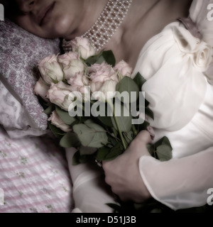 Une femme au lit avec un bouquet de roses roses Banque D'Images