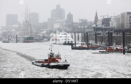 Un remorqueur fonctionnant comme un brise-glace navigue à travers le passage d'expédition dans le port de Hambourg, en Allemagne, pour briser la glace, le 22 décembre 2010. Depuis hier, quatre brise-glace sont en service dans le port. Photo : Malte Chrétiens Banque D'Images