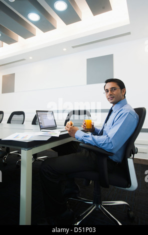 Businessman sitting in office et avoir de la nourriture Banque D'Images