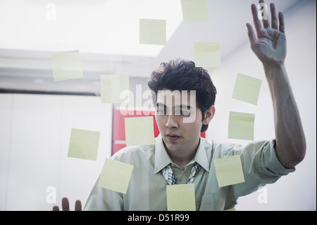 Businessman looking at notes adhésives sur une porte en verre Banque D'Images