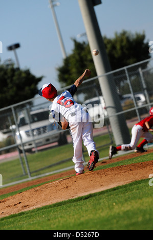 La petite ligue de baseball pitcher lancer au premier but. Banque D'Images