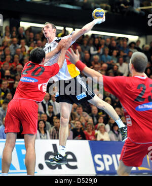 Joueur de handball allemand Holger Glandorf (C) lutte contre les joueurs de l'Autriche Bernd Friede (L) und Kristof Vizvary (R) dans le match de qualification entre l'Allemagne et l'Autriche pour le handball à Goeppingen, Allemagne, 27 octobre 2010. La correspondance a terminé par un match nul. Photo : Bernd Weissbrod Banque D'Images