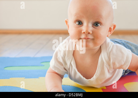 Caucasian baby crawling sur tapis en plastique Banque D'Images