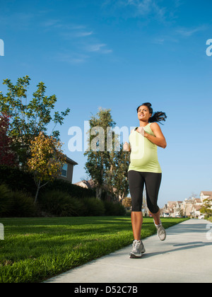 Pregnant Hispanic woman jogging in park Banque D'Images