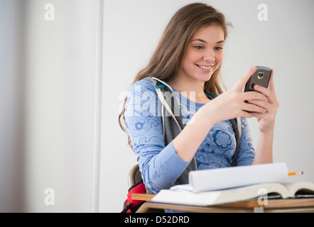 Woman using cell phone at desk Banque D'Images