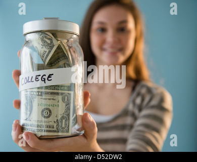 Hispanic girl holding ''college' savings jar Banque D'Images