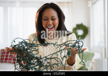 African American Woman démêler les lumières de Noël Banque D'Images