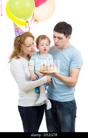 Kid avec parents celebrating birthday et blowing candles on cake Banque D'Images