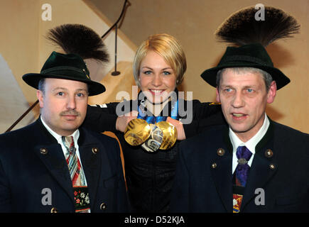 La biathlète Allemande Magdalena Neuner pose avec ses médailles à côté de deux hommes en costume traditionnel au cours de la réception dans sa ville natale Wallgau, Allemagne, 05 mars 2010. Neuner a remporté deux médailles d'or et une médaille d'argent aux Jeux Olympiques d'hiver de 2010 à Vancouver, Canada et est prévu sur une scène spécialement construit sur la place de la ville en fin d'après-midi. Photo : Tobias HASE Banque D'Images