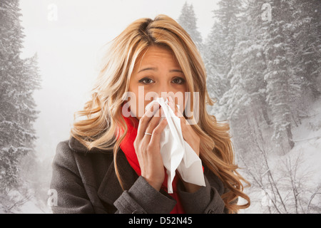 Mixed Race woman blowing her nose in snow Banque D'Images