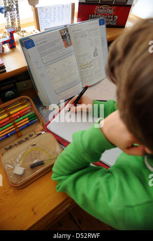 Un garçon est assis sur son bureau et fait ses devoirs à Dresde, Allemagne, 19 mars 2013. Photo : Thomas Eisenhuth Banque D'Images