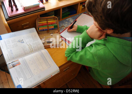 Un garçon est assis sur son bureau et fait ses devoirs à Dresde, Allemagne, 19 mars 2013. Photo : Thomas Eisenhuth Banque D'Images
