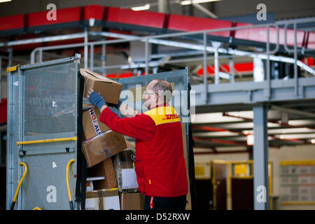 Un employé de Deutsche Post DHL met un paquet sur un panier au premier point de livraison mécanique à Bochum, Allemagne, le 20 mars 2013. C'est le deuxième réseau national qui lit les paquets automatiquement et les distribue au transporteur. Photo : Rolf Vennenbernd Banque D'Images