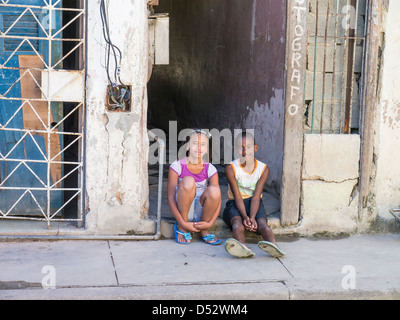 Un jeune garçon et fille cubaine s'asseoir sur la véranda d'une embrasure de La Havane, Cuba. Banque D'Images