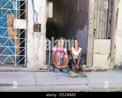 Un jeune garçon et fille cubaine s'asseoir sur la véranda d'une embrasure de La Havane, Cuba. Banque D'Images