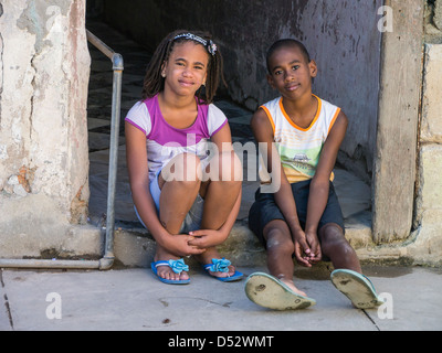 Un jeune garçon et fille cubaine s'asseoir sur la véranda d'une embrasure de La Havane, Cuba. Banque D'Images