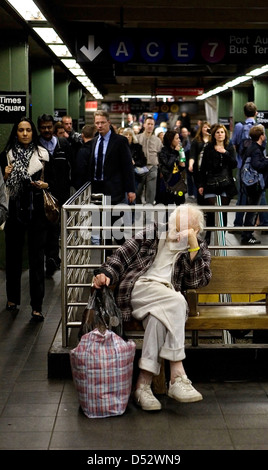 New York City, USA, un homme sans domicile sur un banc de la station de métro à Times Square Banque D'Images