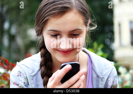 Happy girl avec un téléphone mobile lit le message Banque D'Images