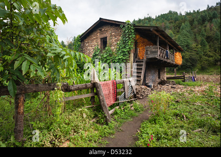 Mur en pierre sèche traditionnelle maison avec des épis de maïs séchant sur la terrasse en plein air, village, Dirang Sangti, Tawang. Banque D'Images