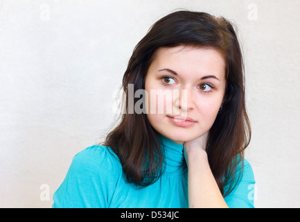 Portrait en gros plan d'une belle jeune fille brune regarde pensivement de côté dans le pull bleu Banque D'Images