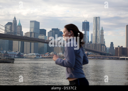 New York City, USA, female jogger sur les bords de l'East River à l'horizon de Manhattan Banque D'Images