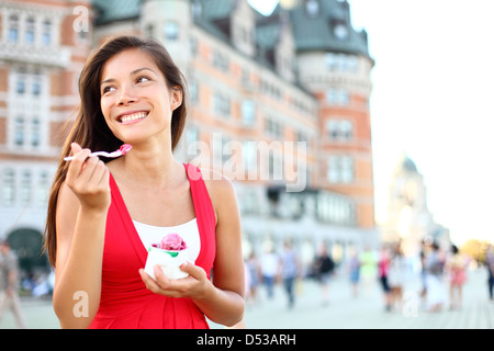 Heureux multicultural Asian Woman in red robe d'été de sourire et de consommation de crème glacée devant le Château Frontenac Banque D'Images