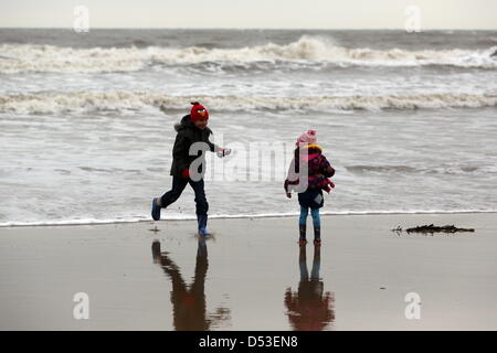 La baie de Langland, Swansea, Royaume-Uni. 23 mars 2013. Frère et sœur Nikolas Ioan, 8 et Sophie Rhian, 4 en cours d'exécution sur la plage dans la baie de Langland, près de Swansea, Pays de Galles du sud à l'état humide et froid matin. Credit : D Legakis / Alamy Live News Banque D'Images