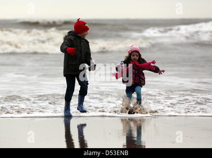 La baie de Langland, Swansea, Royaume-Uni. 23 mars 2013. Frère et sœur Nikolas Ioan, 8 et Sophie Rhian, 4 en cours d'exécution sur la plage dans la baie de Langland, près de Swansea, Pays de Galles du sud à l'état humide et froid matin. Credit : D Legakis / Alamy Live News Banque D'Images