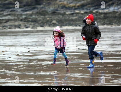 La baie de Langland, Swansea, Royaume-Uni. 23 mars 2013. Frère et sœur Nikolas Ioan, 8 et Sophie Rhian, 4 en cours d'exécution sur la plage dans la baie de Langland, près de Swansea, Pays de Galles du sud à l'état humide et froid matin. Credit : D Legakis / Alamy Live News Banque D'Images