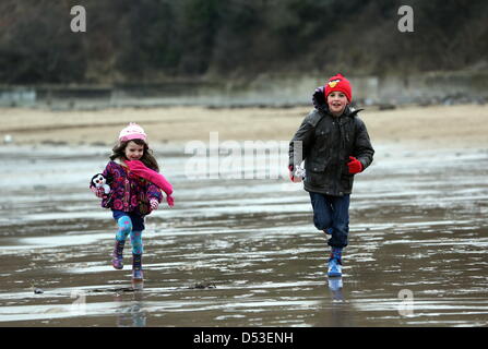 La baie de Langland, Swansea, Royaume-Uni. 23 mars 2013. Frère et sœur Nikolas Ioan, 8 et Sophie Rhian, 4 en cours d'exécution sur la plage dans la baie de Langland, près de Swansea, Pays de Galles du sud à l'état humide et froid matin. Credit : D Legakis / Alamy Live News Banque D'Images