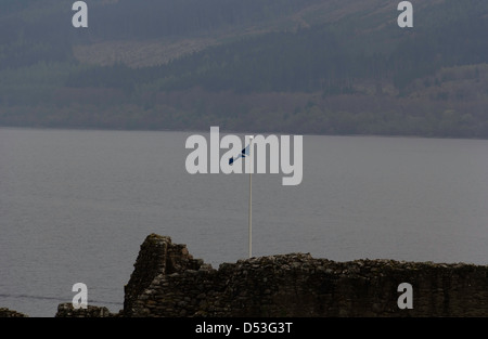 Drapeau écossais, sautoir, de haut vol sur les vestiges d'Urquhart Castle avec les eaux profondes du Loch Ness en arrière-plan. Banque D'Images