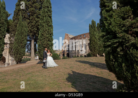 Couple nouvellement marié, debout près de l'Arc de Constantin avec le Colisée en arrière-plan. Rome, Italie Banque D'Images