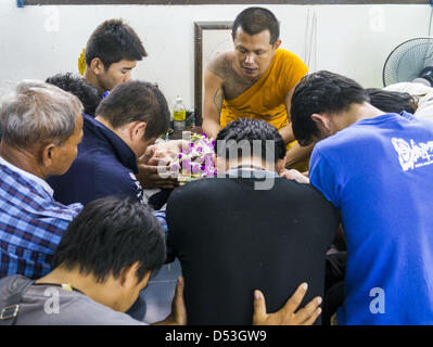 Nakhon Chai Si, Nakhon Pathom, Thaïlande. 22 mars 2013. Les hommes prier et faire des offrandes à une faire après réception de la SAK Yant sacrée au Wat Bang Phra tatouages au cours de l'assemblée annuelle du festival de tatouage. Wat Phra Bang est le plus connu des ''Sak Yant'' tattoo temple en Thaïlande. Il est situé dans la province de Nakhon Pathom, à environ 40 kilomètres de Bangkok. Les tatouages sont donnés avec des aiguilles en acier inoxydable et sont pensées pour posséder des pouvoirs magiques de protection.© ZUMA Press, Inc. / Alamy Live News Banque D'Images