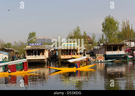 Shikaras jaune en face de péniches dans le lac Dal à Srinagar, paysages. Reflet dans l'eau le long d'arbres et collines. Banque D'Images