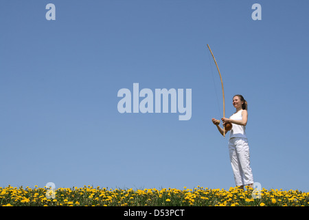 Girl playing berimbau (instrument de musique traditionnel brésilien) dans la floraison printemps pré. Banque D'Images