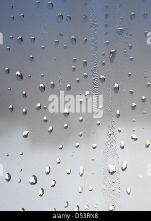 Gouttes d'eau de couleurs métalliques sur le verre. Banque D'Images