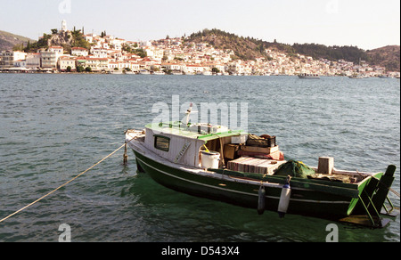 Un bateau de pêche colorés bobs sur les vagues à Galatas, Grèce, avec la ville principale de l'île de Poros visible au-delà. Banque D'Images