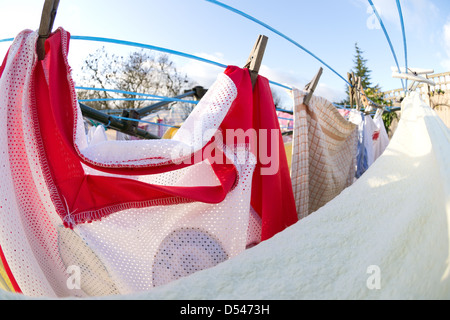 Lave-linge en train de sécher dehors sur journée ensoleillée serviette chiffonnée en premier plan tenu par peg Banque D'Images