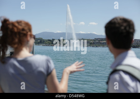 Deux touristes regarder le jet d'eau fontaine d'eau dans la tuyère du lac de Genève, Genève, Suisse Banque D'Images