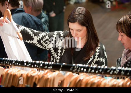 Mère et fille à un shopping vintage vetements juste avec la jeune femme tenant un haut blanc jusqu'en face d'une tringle Banque D'Images