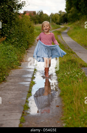 Rühstädt, Allemagne, une jeune fille jouant dans une flaque d'eau sur une route de terre Banque D'Images