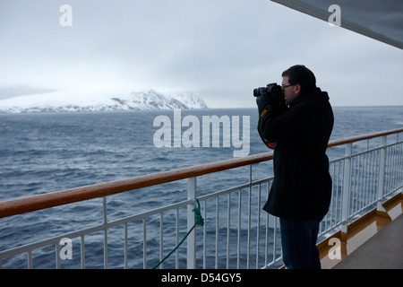 Passager de prendre des photos à bord des navires à passagers hurtigruten voile à travers les fjords en hiver la norvège europe Banque D'Images