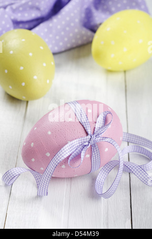 Les œufs de pâques avec ruban violet sur fond de bois blanc Banque D'Images