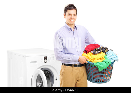 A smiling man avec blanchisserie bin posant à côté d'un lave-linge isolé sur fond blanc Banque D'Images