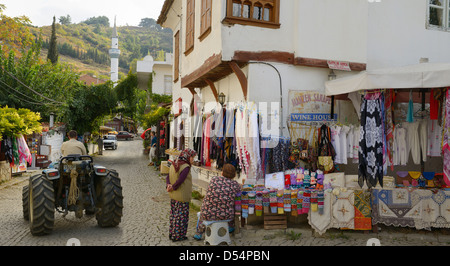 Les femmes du village de plein air situés à parler comme le tracteur passe sur rue pavée de Sirince Turquie Banque D'Images